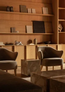 A modern living room featuring wood-paneled walls, marble coffee tables, and plush upholstered chairs.