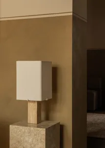Modern minimalist lamp with a beige rectangular shade and a beige marble base, placed on a beige marble pedestal.