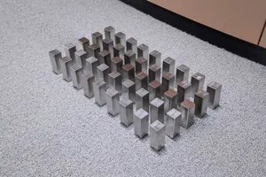 Group of modern metal objects arranged in a pattern on a carpeted floor.