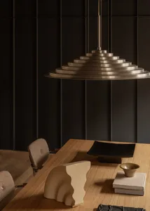 Modern minimalist metal table with geometric design, featuring dark brown wood surface, black plate, gold bowl, and surreal a