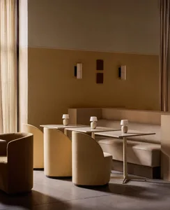 A modern restaurant lounge with fabric seating, concrete tables, and white lampshades.