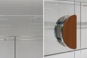 A minimalist office space featuring a glass panel with a wooden element and metallic accents.