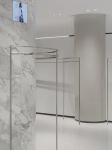 Minimalist retail storefront with white marble walls and metal clothing racks.