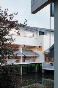 A modern library building with a concrete façade situated by a water body, featuring large windows.