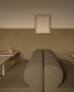 A minimalist interior space with a fabric-covered seating area and plaster walls.