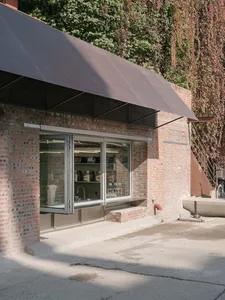 Outdoor view of a brick storefront with an open door, showcasing retail merchandise inside.