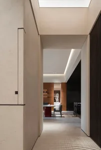 A modern interior corridor featuring concrete walls and ceiling, with a skylight providing natural light and a minimalist des