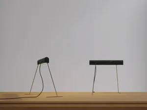 A modern desk lamp with a marble base, lying flat on a wooden surface.