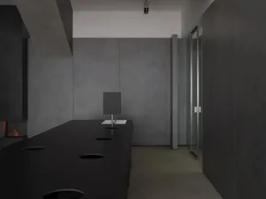 Modern, minimalist office lobby featuring concrete walls and floor, with a glass partition and lighting fixtures.