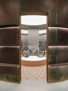 A single bicycle displayed on a white platform within an industrial building.