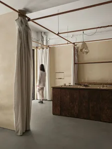 A minimalist interior space featuring fabric blinds hanging from a ceiling rail to create privacy and light control.