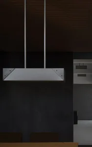 Modern kitchen interior with minimalist design, featuring metal hood and dark wood accents.