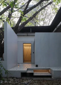 Modern entrance with concrete walls, illuminated by warm light from a geometric lantern