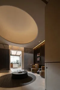 An elegant modern hotel lobby featuring a metal netting and concrete floor, with a circular table and seating area.