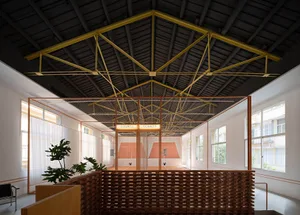 An indoor sports facility with a high ceiling, brick walls, and a grid of metal tubing dividing the space into two courts.