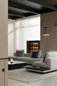 A modern living room featuring a fabric sofa with wooden accents and a chalkboard desk, illuminated by natural light through 