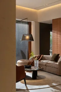 A modern living room featuring a large beige sectional sofa adorned with brown and green throw pillows, a glass liquor bowl, 