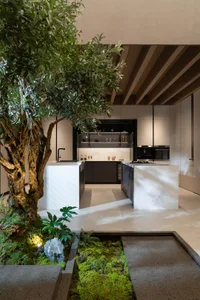 A modern minimalist kitchen featuring marble counters and white cabinets.
