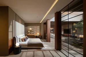 A modern bedroom with a white bed and neutral-colored decor, featuring a glass wall with a green plant.
