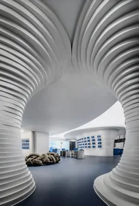 Modern office space with carpeted floor and white columns, featuring a curved ceiling and contemporary design elements.