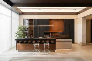 A modern residential kitchen featuring wood and metal materials, with a central island and stools.