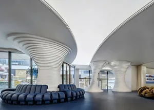 A modern retail storefront featuring curved white structures and a blue sofa in the foreground.
