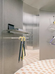 A modern interior space with perforated metal walls and a geometric floor pattern.
