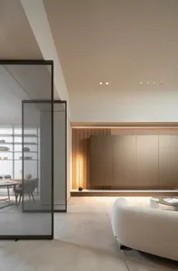 A modern minimalist living room with light-colored flooring, wooden paneling, and a white sofa.
