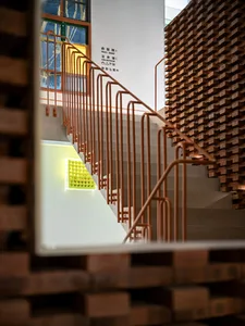 A modern staircase features metal railings and a brick wall.