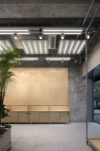 An industrial-style office space with concrete walls, wood cabinets, and fluorescent lighting.