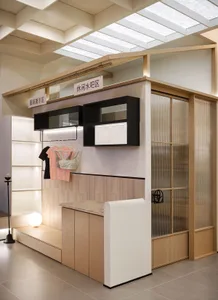 A minimalist retail storefront with a wood finish, featuring clothing racks and an illuminated storage area.