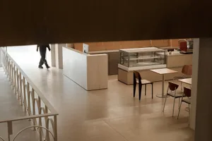 Modern cafe interior with white-washed wooden tables and chairs, concrete flooring, and metal elements.