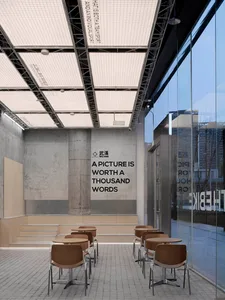 A modern coffee shop with concrete walls and floor, featuring metal structures and tables with chairs.