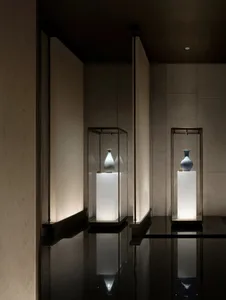 現代展覽空間內，透明玻璃展示櫃陳列花瓶，置於大理石基座上。