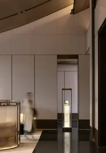 A spacious hotel lobby with sleek, metallic and glass design elements, illuminated by warm lighting.