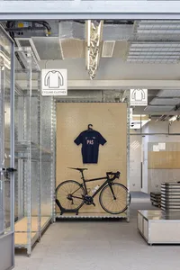 A modern industrial-style cycling clothes store with metallic shelving and glass doors.