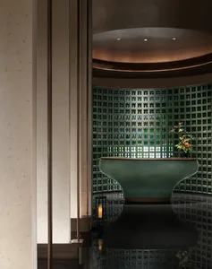 Modern spa interior with glass brick wall and a green ceramic bathtub in the foreground.