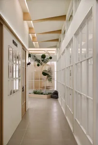 Modern, minimalist corridor featuring glass walls and ceiling beams.