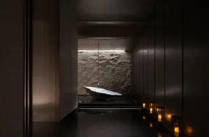 A minimalist spa room featuring concrete walls and illuminated candles.