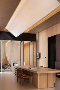 A modern living room with wooden furniture and a high, sloped ceiling with recessed lights.