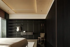 Minimalist bedroom with black wood walls and ceiling, light-colored bed and rug, and floating shelves with clothes.