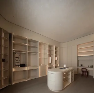 A modern, white walk-in closet with minimalistic design, featuring light wooden flooring and illuminated shelves.