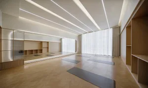 寬敞的瑜伽工作室採用極簡設計，搭配木質地板與白色窗簾。