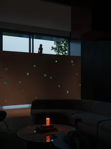 A minimalist modern living room featuring concrete walls and surfaces, with a large circular coffee table and a silhouette of