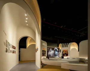 Industrial exhibition space featuring a white concrete design with curved arches and illuminated interiors.