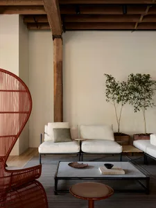 A comfortable and modern living room with exposed wooden beams, upholstered furniture, and potted plants.