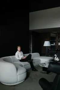 A minimalist living room featuring a white sofa, black coffee table, and dark, modern flooring.