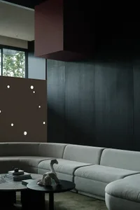 Modern living room featuring a cushioned sofa against a dark, minimalist background with a large window.