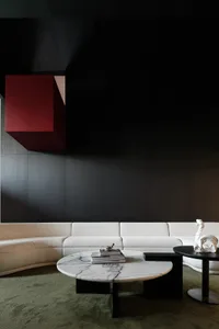 Modern living room with white and red modular seating, a round marble coffee table, and dark green carpet.