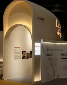 White exhibition booth with curved archways and illuminated signs.